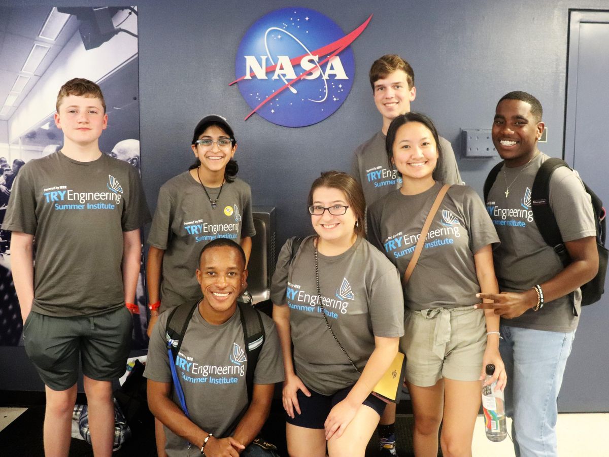 一群人站在一面墙前的照片，墙上有NASA的标志。