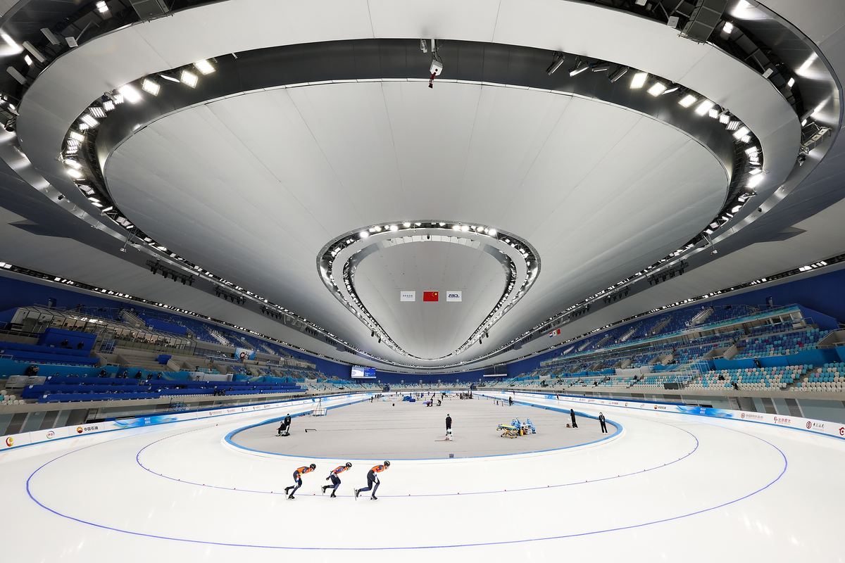 一张大型溜冰场内部的照片，前景中有三个溜冰者