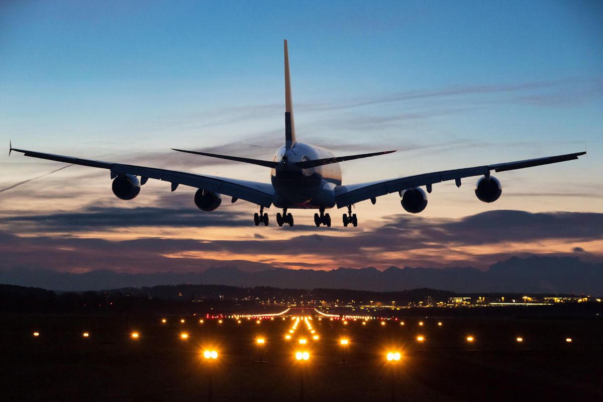 一架飞机在清晨即将着陆。在前景中可以看到跑道灯。