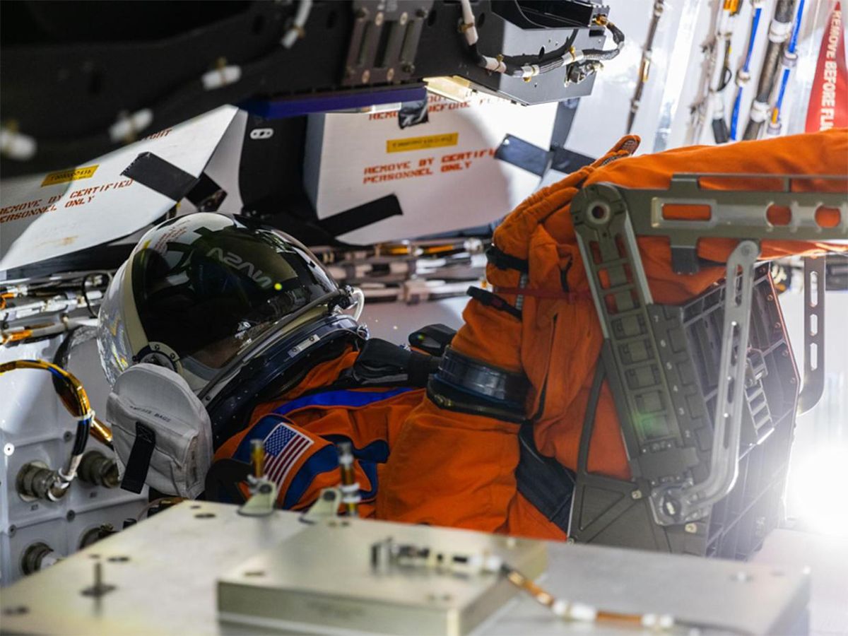 在狭窄的太空舱里，一件橙色的救生太空服斜倚着