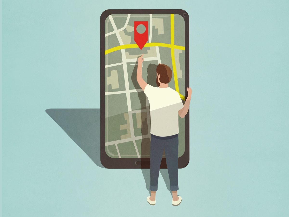 一个人看着巨大的智能手机，上面有地图和红色的“你在这里”标志