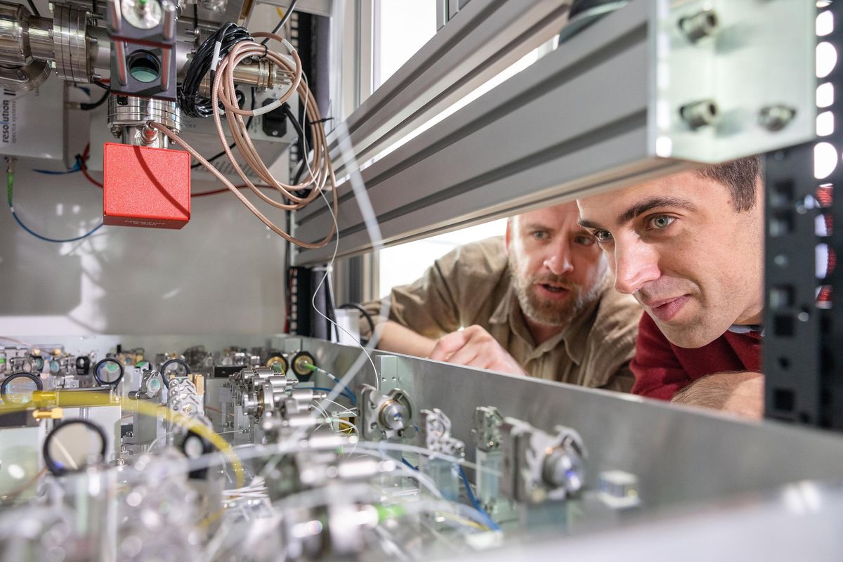 两个男人凝视着一个装有复杂光学装置的柜子